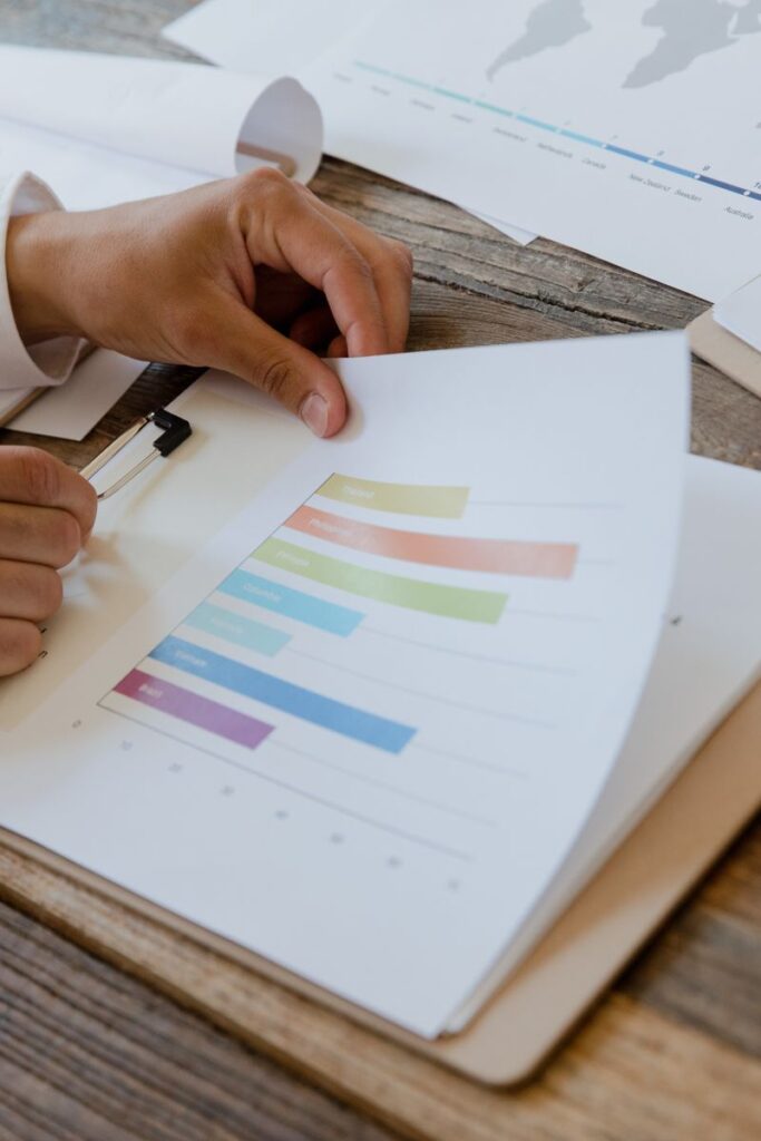 Close-up of hands reviewing business report with colorful charts and graphs on a wooden desk.